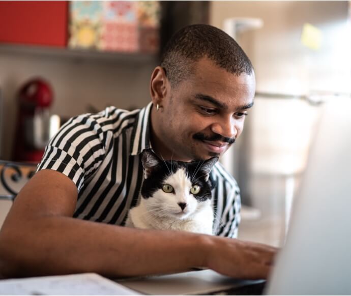 고양이를 안고 노트북을 사용 중인 남자
