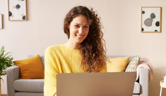 Norton Safe Search를 실행하는 노트북을 사용하면서 웃고 있는 여성.